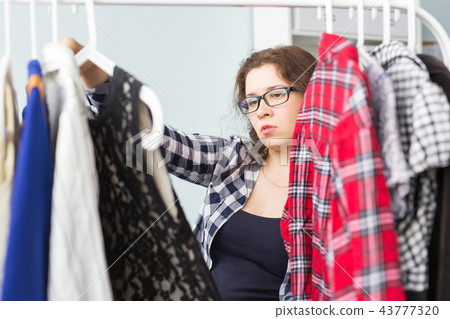 Clothing, fashion, style and people concept - woman choosing clothes at home wardrobe Clothing, fashion, style and people concept - woman choosing clothes at home wardrobe 43777320