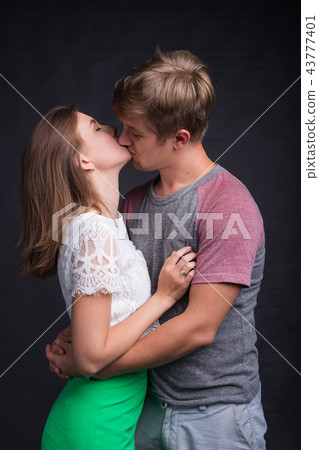 Beautiful young couple hugging and kissing isolated on black background. Beautiful young couple hugging and kissing isolated on black background. 43777401