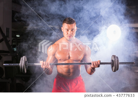 Handsome power athletic man with barbell. Strong bodybuilder with six pack, perfect abs, shoulders 43777633
