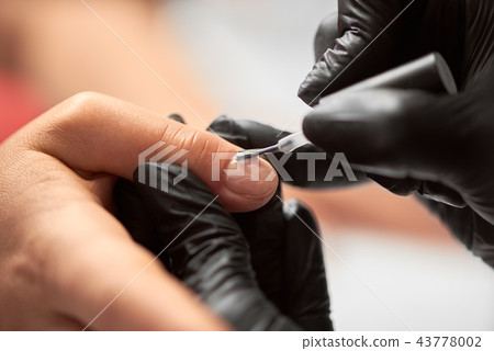 Close-up of beautician hands applying transparent gel polish on woman fingernails in beauty salon. Close-up of beautician hands applying transparent gel polish on woman fingernails in beauty salon. 43778002
