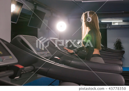 Fitness woman running on treadmill. Girl with muscular legs in gym 43778350