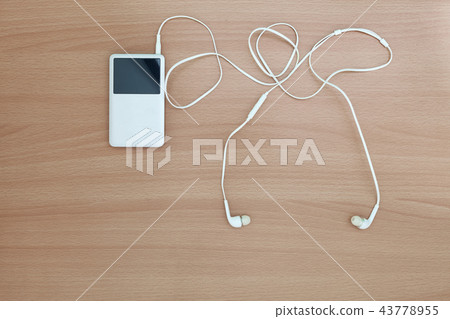 Music player with white earphone on wood Music player with white earphone on wood 43778955