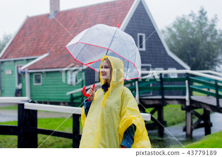 girl in rain suit with umbrella stay on bridge with dutch house 43779189
