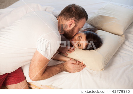 a man wakes up in the morning a woman tenderly kisses 43779580