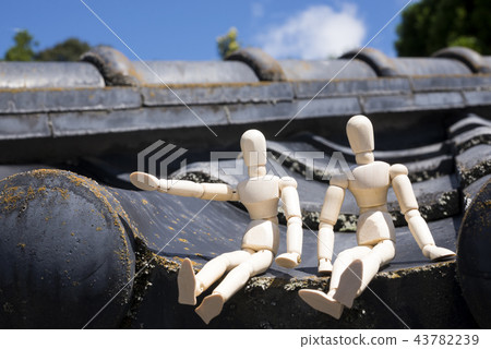 Two dolls sitting on a tiled roof Two dolls sitting on a tiled roof 43782239
