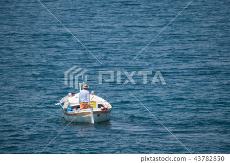 Fisherman in traditional wooden boat at sea Fisherman in traditional wooden boat at sea 43782850