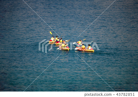 Mixed group of people, facing away, unrecogizable, canoeing at sea 43782851