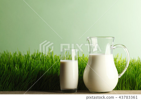 Glass of milk and jar on meadow 43783361