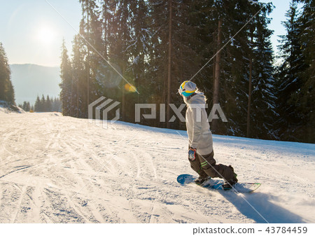 Young woman snowboarding on the slope on a beautiful winter sunny evening copyspace sunlight sunset Young woman snowboarding on the slope on a beautiful winter sunny evening copyspace sunlight sunset 43784459