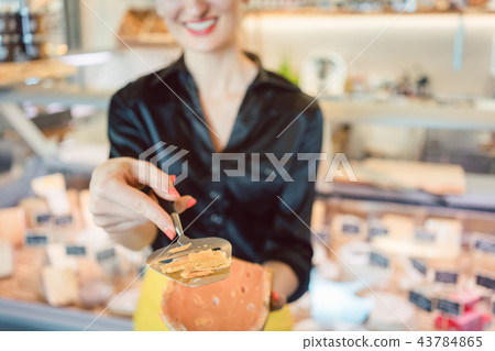 Beautiful woman offering cheese on delicatessen counter Beautiful woman offering cheese on delicatessen counter 43784865