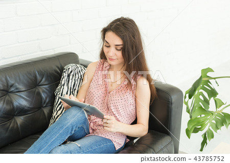 Technologies, people concept - young woman sitting on sofa and watching the laptop or surfing the 43785752