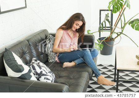 People, working and technology concept - relaxed young woman sitting on sofa with tablet People, working and technology concept - relaxed young woman sitting on sofa with tablet 43785757