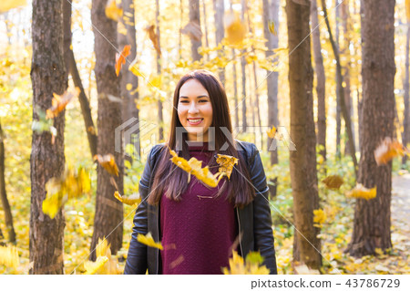 Fall, beauty, people concept - young woman posing in autumn park with falling leaves 43786729