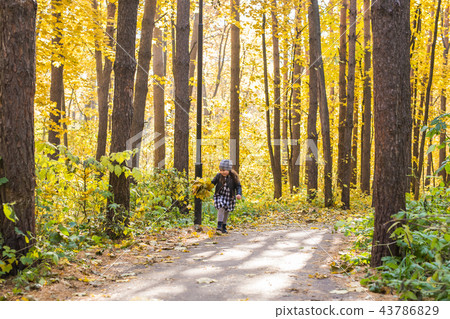 Autumn, happiness and people concept - child running through autumn park with yellow leaves in her Autumn, happiness and people concept - child running through autumn park with yellow leaves in her 43786829