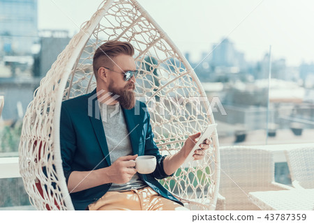 Calm male using phone and tasting liquid Calm male using phone and tasting liquid 43787359