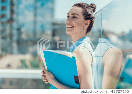 Satisfied female holding documents in arms outdoor Satisfied female holding documents in arms outdoor 43787900