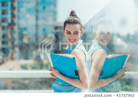 Pleased girl keeping folders with the information Pleased girl keeping folders with the information 43787902
