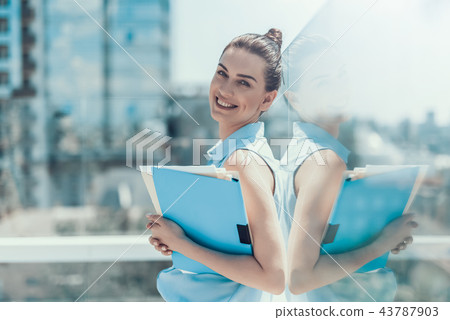 Cheerful female holding the documents in arms Cheerful female holding the documents in arms 43787903