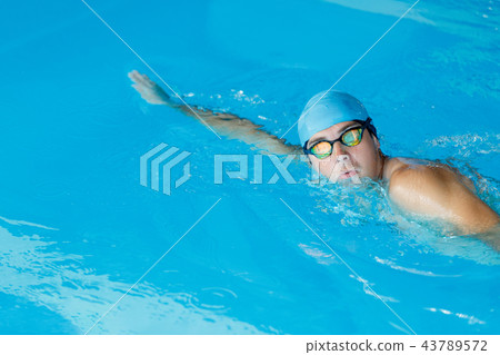 Portrait of sportive man in blue cap floating in pool 43789572