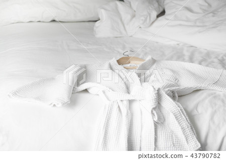 white bath robe on the bed in hotel room 43790782