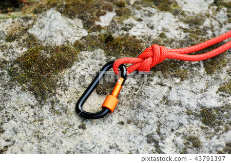 Carabiner on rocky background. Carabiner on rocky background. 43791397