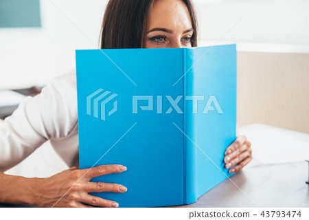 Female student hiding behind an open book 43793474
