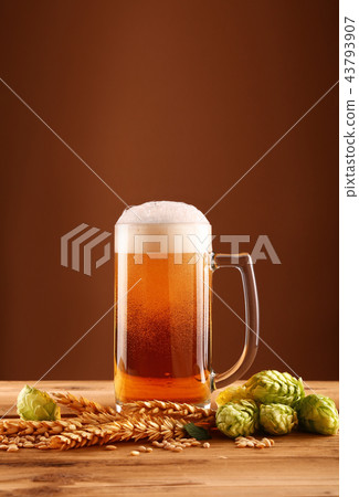 Close up beer glass, hops and barley over brown Close up beer glass, hops and barley over brown 43793907