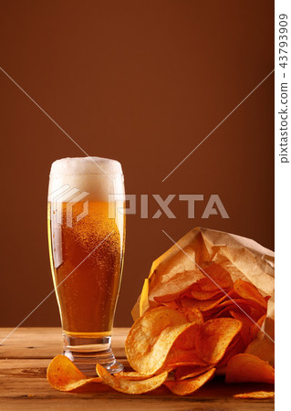 Close up beer glass and potato chips over brown 43793909
