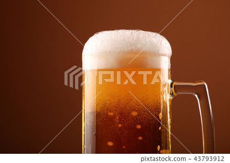 Close up pouring frothy beer in glass over brown 43793912