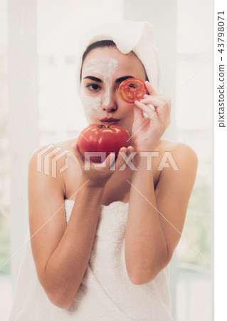 Woman get facial mask with tomato cream extract. 43798071
