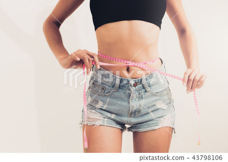 Slim woman measures her waist with measuring tape. 43798106