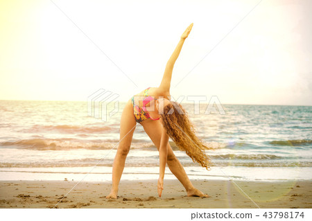 Young woman practices yoga on the beach in summer. 43798174