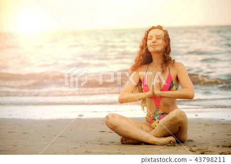 Young woman practices yoga on the beach in summer. 43798211
