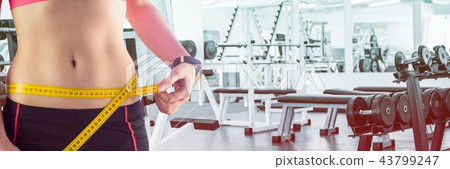 Fit Woman with measuring tape around waist in fitness studio 43799247