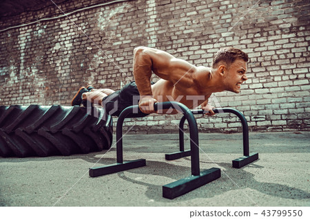 Strong sporty happy cheerful positive man doing press exercises holding plank outdoors Strong sporty happy cheerful positive man doing press exercises holding plank outdoors 43799550