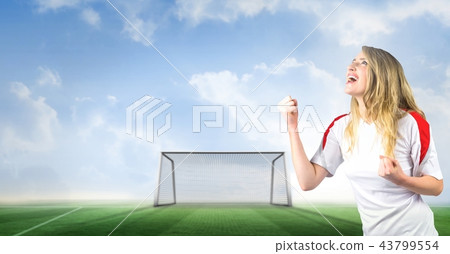 Soccer fan celebrating with fist and goal on pitch 43799554