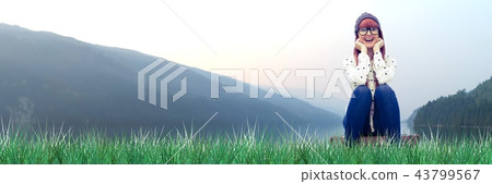 smiling woman sitting on suitcase in field 43799567