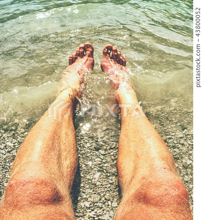 Hairy strong male legs are cooling in cold water Hairy strong male legs are cooling in cold water 43800052