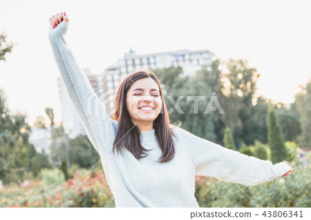 Young attractive woman in light colored sweater welcoming and trying to hug the viewer 43806341
