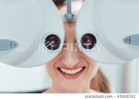 Woman having her eyesight measured with phoropter Woman having her eyesight measured with phoropter 43808381