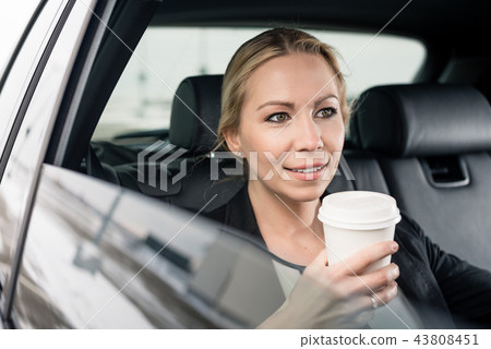 Businesswoman holding coffee cup sitting in the car Businesswoman holding coffee cup sitting in the car 43808451