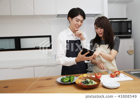 Couple searching the net with a tablet on the tablet and cooking Couple searching the net with a tablet on the tablet and cooking 43808549