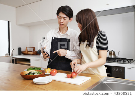 Couple searching the net with a tablet on the tablet and cooking 43808551