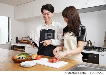 Couple searching the net with a tablet on the tablet and cooking Couple searching the net with a tablet on the tablet and cooking 43808552