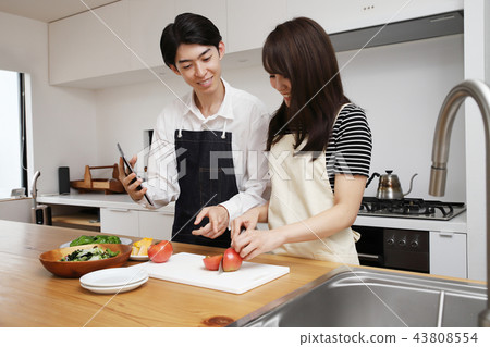 Couple searching the net with a tablet on the tablet and cooking 43808554