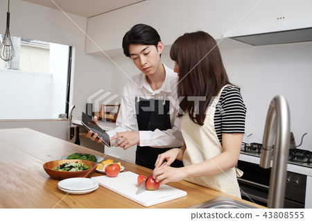 Couple searching the net with a tablet on the tablet and cooking 43808555