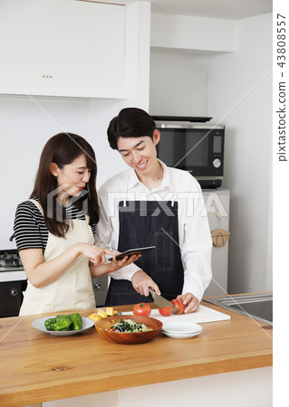 Couple searching the net with a tablet on the tablet and cooking Couple searching the net with a tablet on the tablet and cooking 43808557