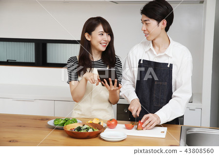 Couple searching the net with a tablet on the tablet and cooking Couple searching the net with a tablet on the tablet and cooking 43808560