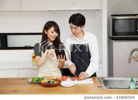 Couple searching the net with a tablet on the tablet and cooking Couple searching the net with a tablet on the tablet and cooking 43808564