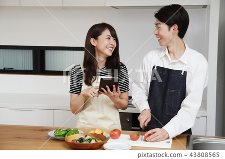 Couple searching the net with a tablet on the tablet and cooking Couple searching the net with a tablet on the tablet and cooking 43808565